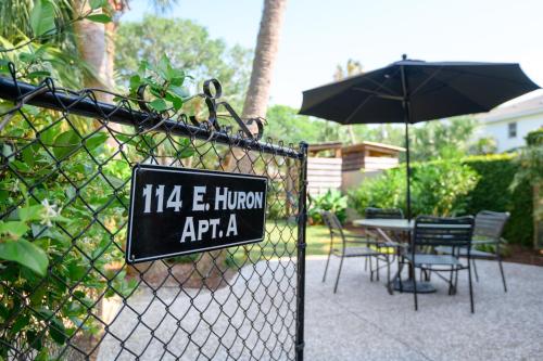 uma placa em uma cerca com uma mesa e um guarda-chuva em Folly Vacation 114A Townhouse near the beach, pet friendly em Folly Beach