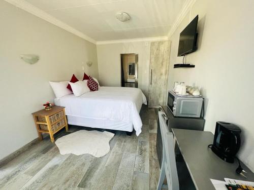 a bedroom with a white bed and a tv at Hillas Ridge Guesthouse in Vanderbijlpark