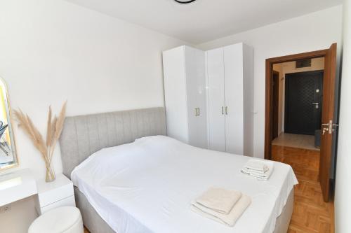 a small bedroom with a white bed and a mirror at Apartman Dina in Pirot
