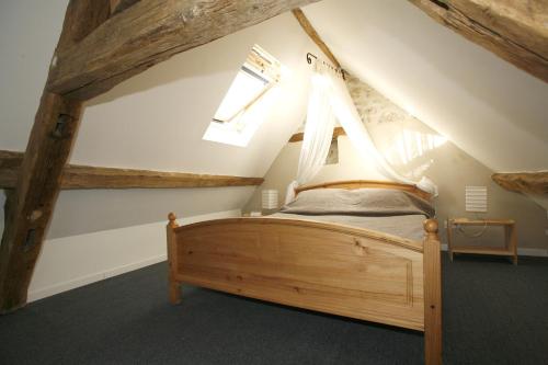 - une chambre mansardée avec un lit en bois dans l'établissement gitesevin F3B, à Saint-Forget