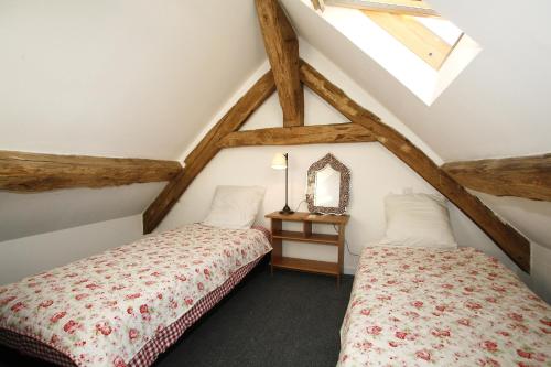 Cette chambre mansardée comprend 2 lits et un miroir. dans l'établissement gitesevin F3B, à Saint-Forget
