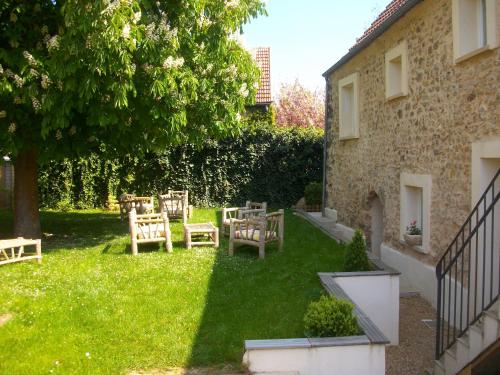 une cour avec des chaises et un arbre à côté d'un bâtiment dans l'établissement gitesevin F3B, à Saint-Forget