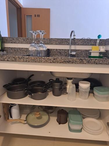 a kitchen shelf filled with pots and pans at Guarajuba Paraiso dos Coqueiros B02 in Camaçari
