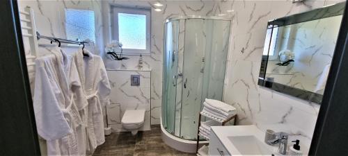 a bathroom with a shower and a sink and a mirror at Apartamenty Dżemejra - Jumeirah in Darłowo