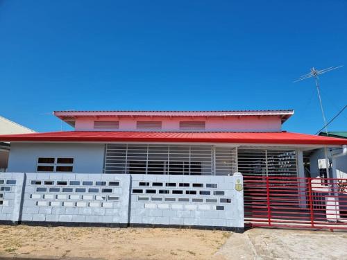 una casa con techo rojo y valla blanca en Luxe woning in Paramaribo Zuid / Casa Birambie, en Paramaribo