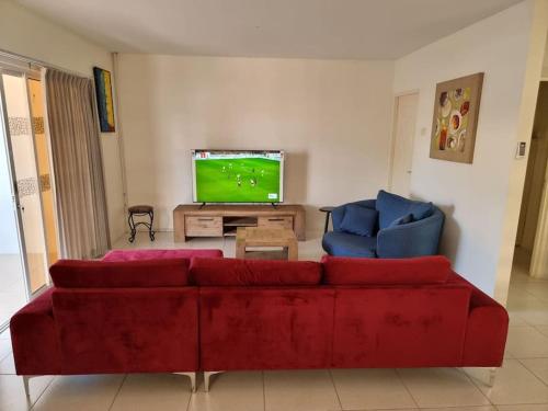 sala de estar con sofá rojo y 2 sillas azules en Luxe woning in Paramaribo Zuid / Casa Birambie, en Paramaribo