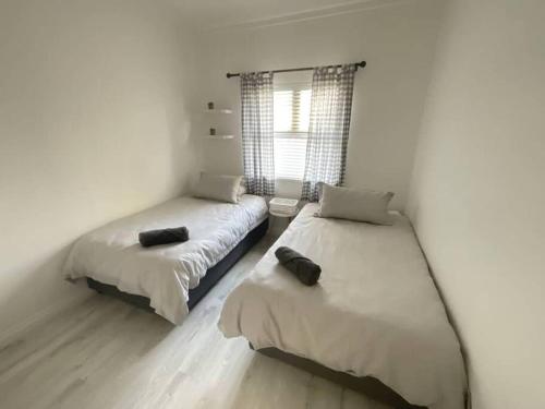 two beds in a room with white walls at Palm Self Catering - House in Walvis Bay in Walvis Bay