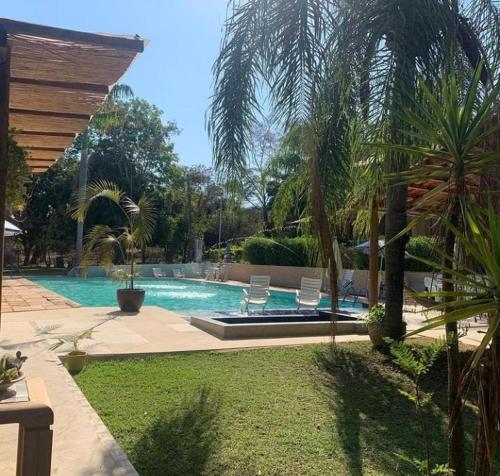 a swimming pool with two chairs and a swimming pool at Hotel Fazenda Tia Dora in Três Marias