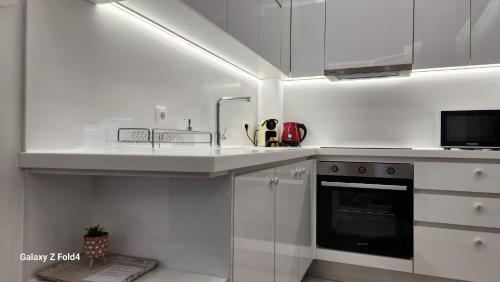 - une cuisine blanche avec évier et cuisinière dans l'établissement De lenco Residence 4, à Athènes
