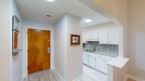 a kitchen with white cabinets and a wooden door at Tall Pines Villa River Club Golf Views in Pawleys Island