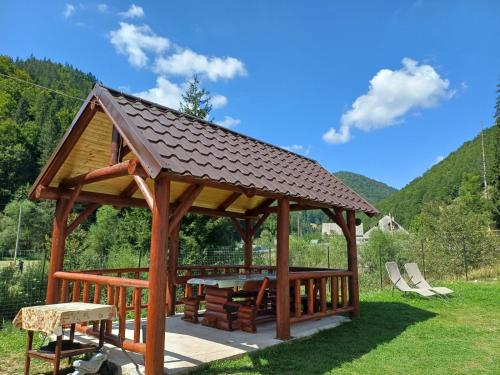 einen hölzernen Pavillon mit einem Dach auf dem Gras in der Unterkunft Cabana Acasă la Delia in Gârda de Sus