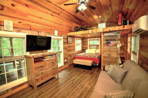 a living room with a couch and a tv in a log cabin at The Americana - Parker Creek Bend Cabins in Murfreesboro