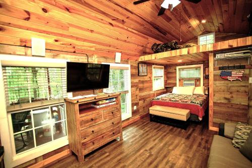 um quarto com uma cama e uma televisão num chalé de madeira em The Americana - Parker Creek Bend Cabins em Murfreesboro