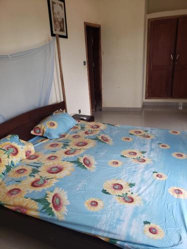 a bed with a blue comforter with flowers on it at Agimdeluxe in Abomey-Calavi