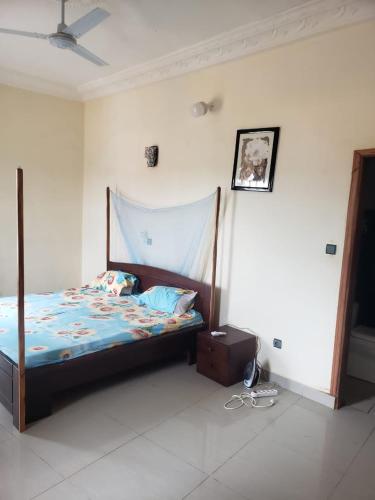 1 dormitorio con 1 cama con marco de madera en Agimdeluxe en Abomey-Calavi