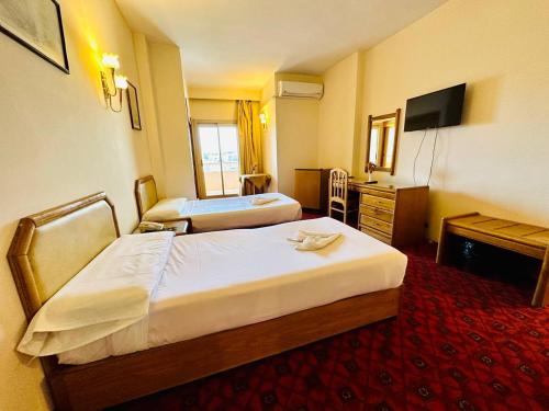 a hotel room with two beds and a television at Queens Valley Hotel in Luxor