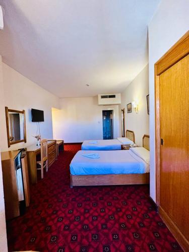 a hotel room with two beds and a red carpet at Queens Valley Hotel in Luxor