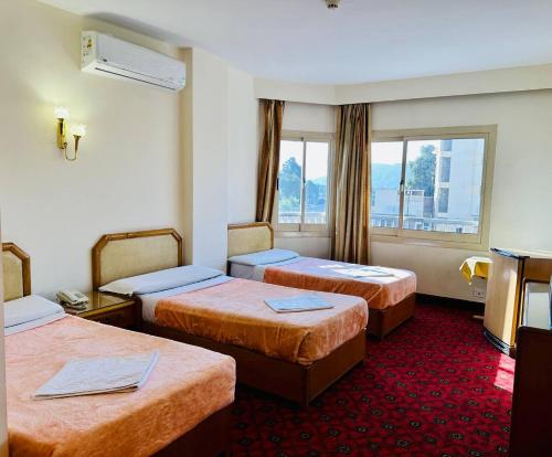 Queens Valley Hotel في الأقصر: غرفه فندقيه ثلاث اسره ونافذه