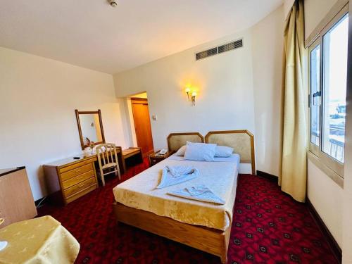 a bedroom with a bed and a desk and a window at Queens Valley Hotel in Luxor