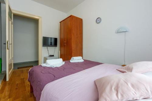 a bedroom with a purple bed and a tv at Room Laura in Crikvenica