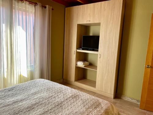 a bedroom with a bed and a cabinet with a television at Entre Rieles Cabañas y Restaurante in Calama