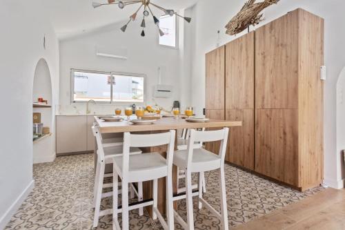 uma cozinha com uma mesa de madeira e cadeiras brancas em Charming townhouse with air conditioning in Anglet - Welkeys em Anglet