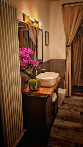 un bagno con un lavandino e fiori rosa su un bancone di Casa22 ad Abbadia San Salvatore