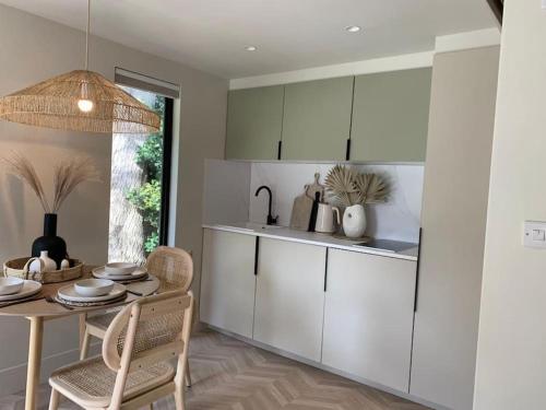 a kitchen with white cabinets and a table with chairs at West Wittering Beach Getaway in West Wittering
