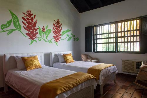 a bedroom with two beds and a painting on the wall at Sotovocce Casa Campestre in Turbaco