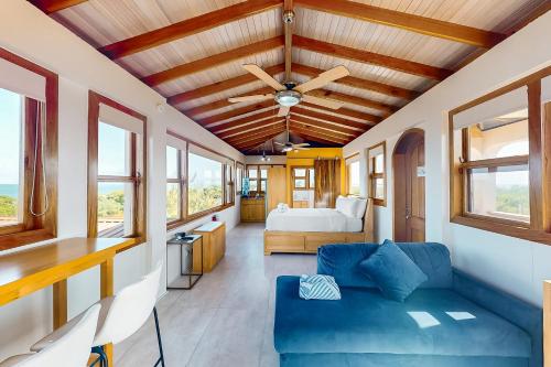 a living room with a blue couch and a bed at Suite 3 at Island Pearl Gold Standard Certified in Caye Caulker