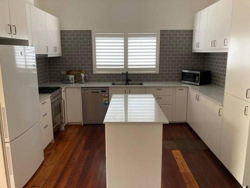 a kitchen with white cabinets and a white counter top at The Goody House in Unley