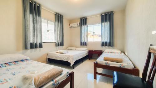 um quarto com duas camas e uma cadeira em CASA NA RUA DO PIRUÍ EM AREMBEPE com ar em Arembepe