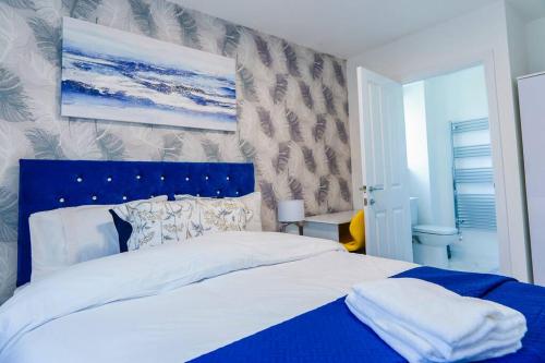 a bedroom with a large bed with a blue headboard at Caasi Homes in Leigh