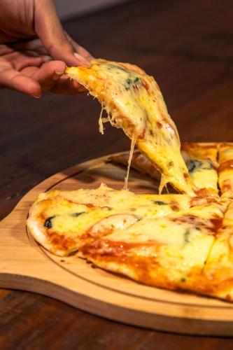 a person is holding a slice of cheese pizza at Chill Out Hostel in Boracay