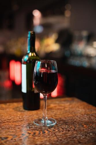 um copo de vinho tinto sentado ao lado de uma garrafa de vinho em Apt Rústico Maravilhoso em Vitória da Conquista