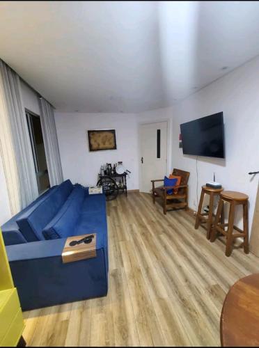 uma sala de estar com um sofá azul e uma televisão de ecrã plano em Apt Rústico Maravilhoso em Vitória da Conquista