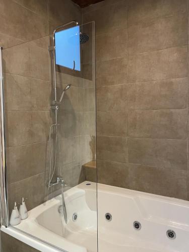 a bath tub with a shower with a glass door at Surf Lodge Punta de Lobos in Pichilemu