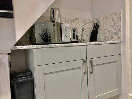 a kitchen with white cabinets and a counter with a microwave at Brighton Palms in Brighton & Hove