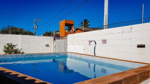 a swimming pool in front of a white wall at CASA NA RUA DO PIRUÍ EM AREMBEPE com ar in Arembepe