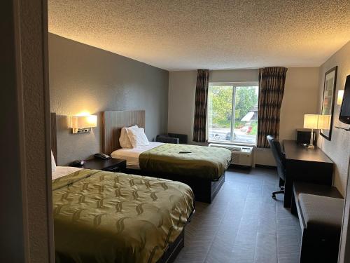Habitación de hotel con 2 camas, escritorio y ventana en BlissPoint Inn Northwest Indianapolis en Indianápolis