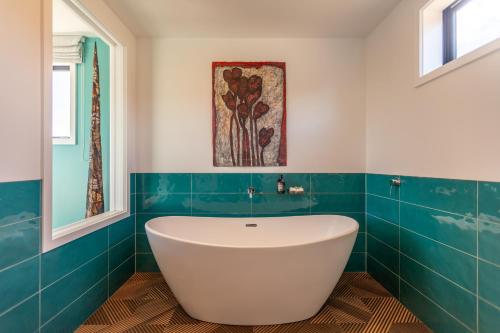a bath tub in a bathroom with blue tiles at Ono in Te Horo