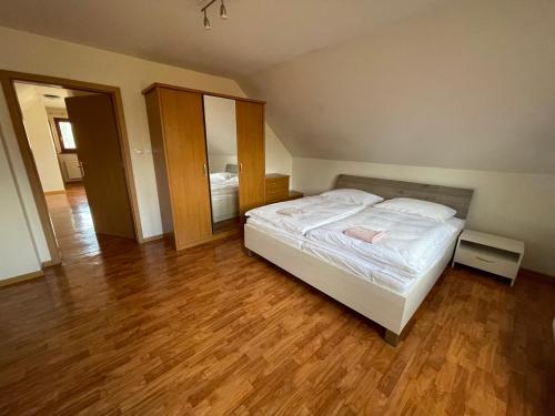 a bedroom with a white bed and a wooden floor at Dom Príbovce in Príbovce