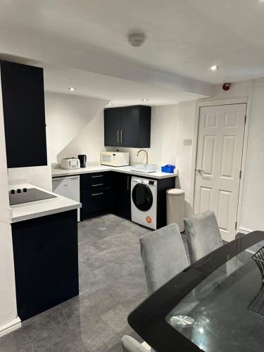 a kitchen with black and white appliances and a table and chairs at Modern 2 Bedroom Apt Derby City in Derby