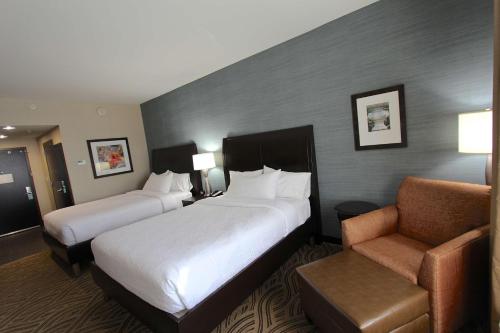 a hotel room with two beds and a chair at Hilton Garden Inn Findlay in Findlay