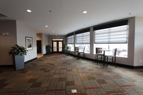 an empty lobby with tables and chairs and windows at Hilton Garden Inn Findlay in Findlay