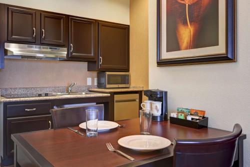 a kitchen with a wooden table with plates and glasses on it at Homewood Suites by Hilton Denver Tech Center in Englewood