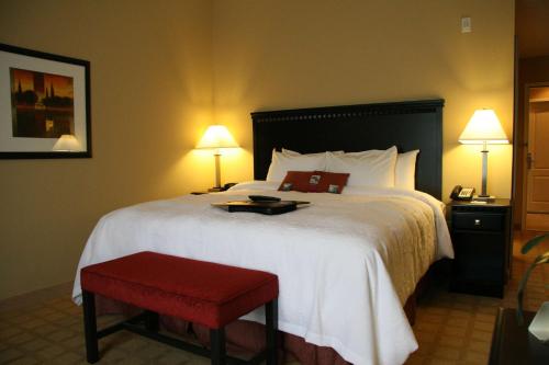 Cette chambre d'hôtel comprend un grand lit avec un tabouret rouge. dans l'établissement Hampton Inn Dade City - Zephyr Hills, à Dade City