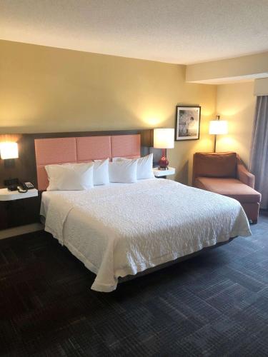 a hotel room with a large bed and a chair at Hampton Inn & Suites Norfolk-Airport in Norfolk