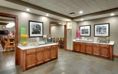 una cocina con armarios de madera y una barra en un restaurante en Hampton Inn & Suites Pocatello, en Pocatello