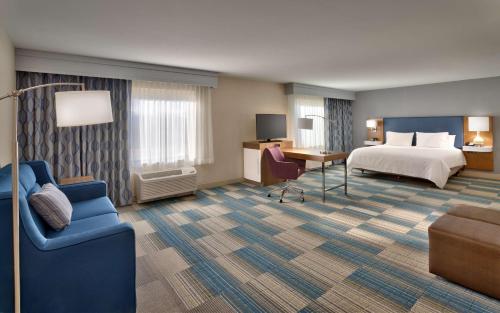 a hotel room with a bed and a desk and a couch at Hampton Inn & Suites Pocatello in Pocatello